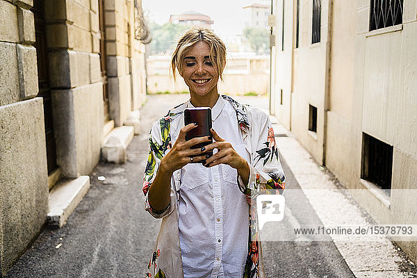 Smiling woman using smartphone in the city