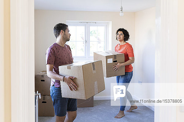 Couple moving into new home carrying cardboard boxes