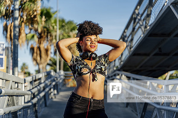 Weibliche Afroamerikanerin mit Kopfhörern genießt Sonnenlicht