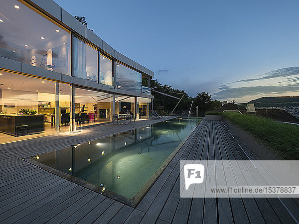 Schweiz  beleuchtete moderne Villa in der Abenddämmerung mit Terrasse und Pool im Vordergrund