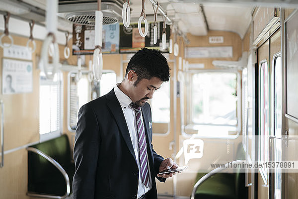 Young businessman using cell phone on a train