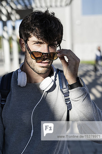 Portrait of cool man with sunglasses and headphones in the city