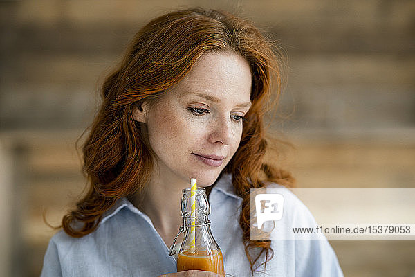 Porträt einer rothaarigen Frau  die Saft trinkt