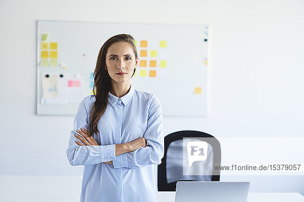 Portrait of confident businesswoman looking at camera with crossed arms in office