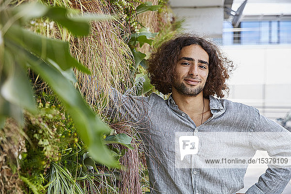 Portrait of young man in front of plant wall
