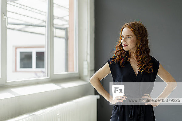 Portrait of redheaded businesswoman in a loft looking out of window