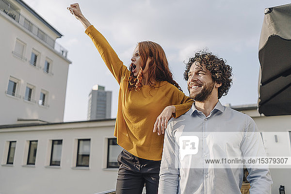 Woman with colleague on roof terrace clenching fist