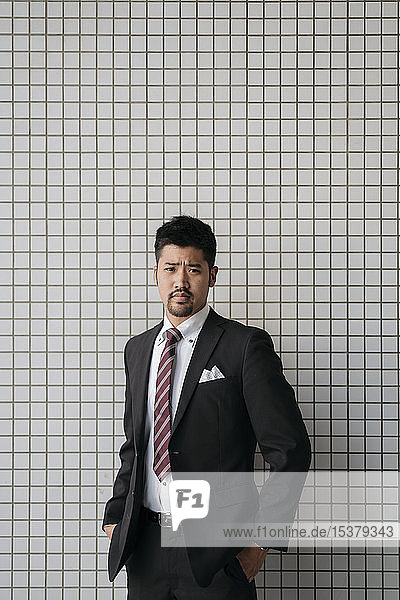 Portrait of confident young businessman at tiled wall