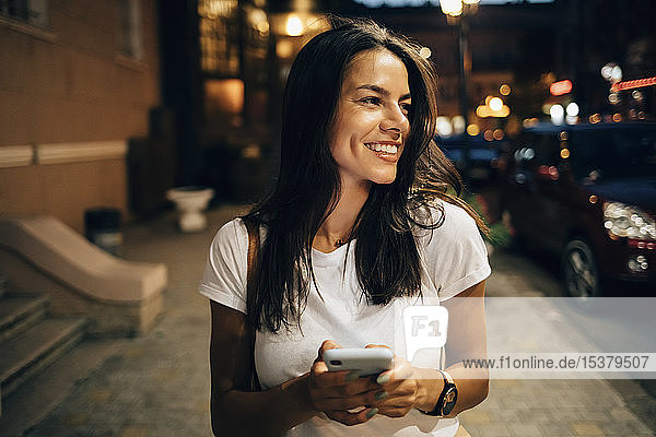 Young woman using smartphone in the city at night