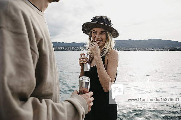 Glückliches junges Paar bei einem Drink an einem See