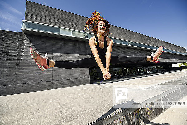 Fröhliche sportliche junge Frau springt in einem modernen Gebäude