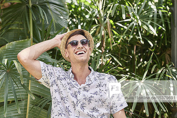 Lächelnder Mann mit Hut und Sonnenbrille in einem Park
