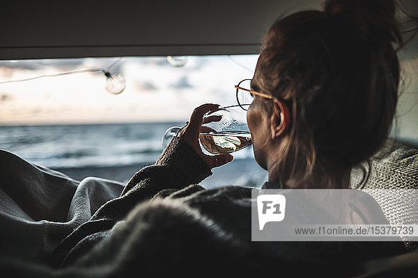 Young woman with glass of white wine in van