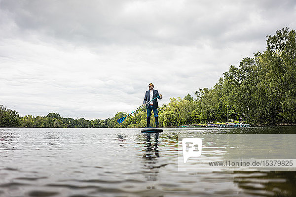 Businessman stand up paddling on a lake