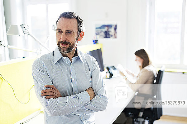 Porträt eines selbstbewussten Geschäftsmannes im Amt mit Mitarbeiter im Hintergrund