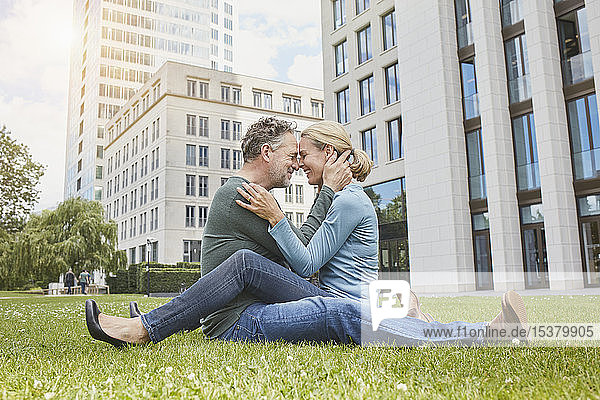 Glückliches reifes Paar kuschelt auf dem Rasen in der Stadt
