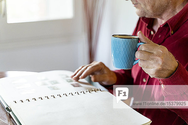 Älterer Mann schaut zu Hause auf Briefmarkensammlung