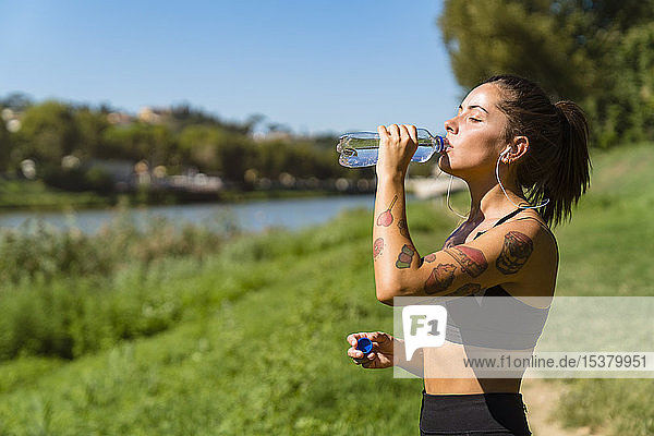 Sportliche junge Frau bei einer Abkühlungspause am Flussufer