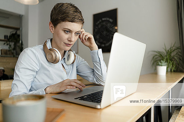 Geschäftsfrau mit Kopfhörern mit Laptop in einem Café