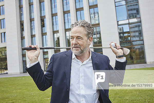 Mature businessman with golf club in the city