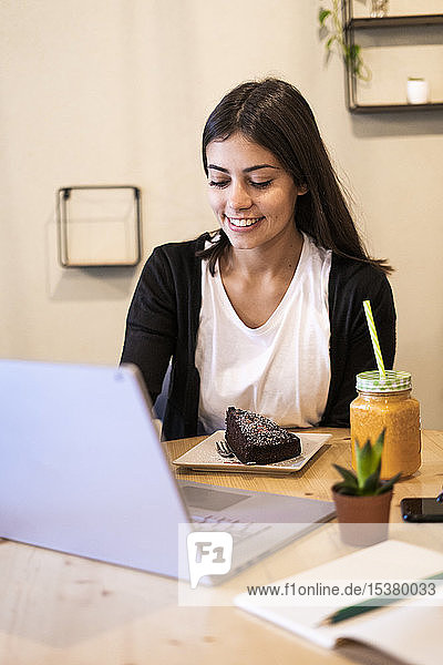 Lächelnde junge Frau mit Laptop in einem Cafe