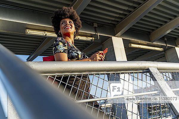 Lächelnde afro-amerikanische Frau mit rotem Smartphone