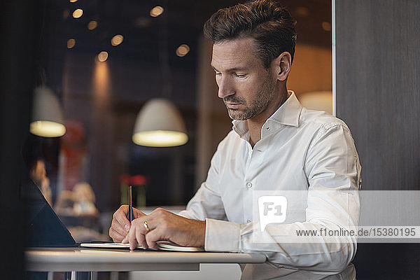 Businessman with tablet in a cafe taking notes