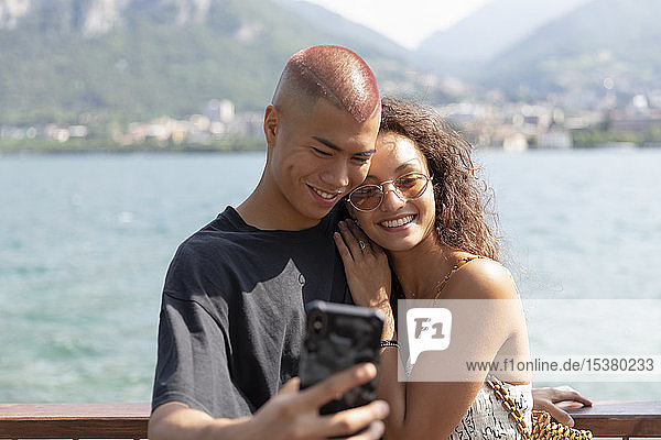 Portrait of happy young couple taking selfie in front of Lake Como  Lecco  Italy