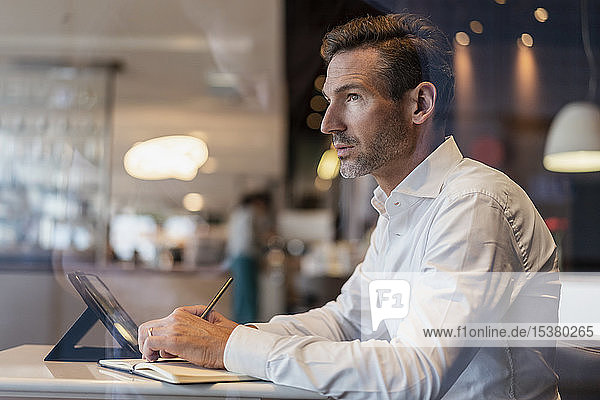 Businessman with tablet in a cafe taking notes