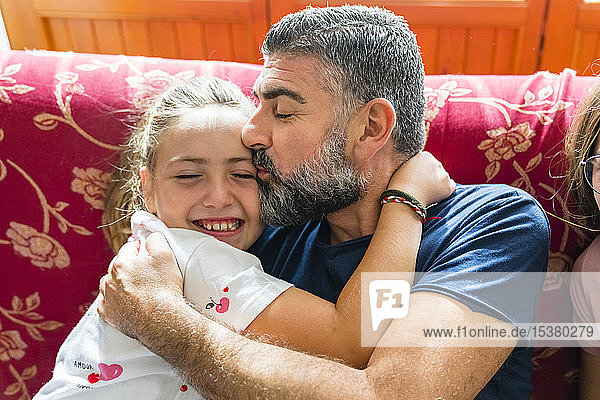 Father hugging with daughter on couch at home