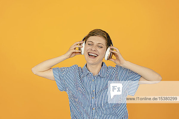 Porträt einer glücklichen Frau  die Musik mit orangem Hintergrund hört