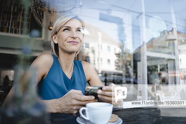 Geschäftsfrau macht Pause im Café  hält Smartphone