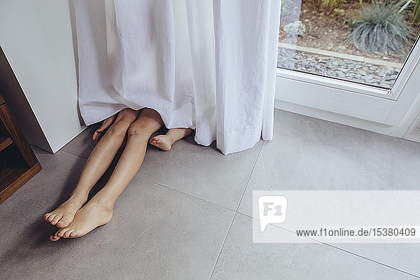 Beine und Füße von Kindern  die sich hinter einem Vorhang verstecken