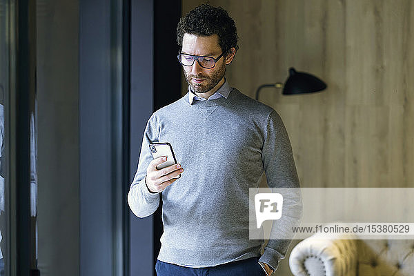 Serious businessman checking cell phone