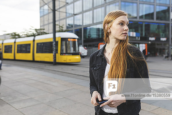 Rothaarige junge Frau wartet am Alexanderplatz  Berlin  Deutschland