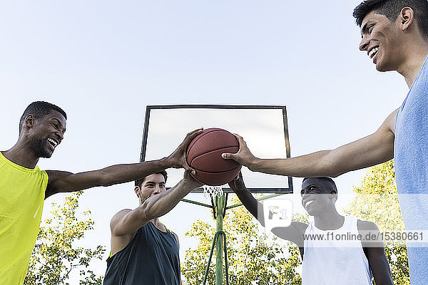 Group of multiracial men holding basketball all together  low angle view