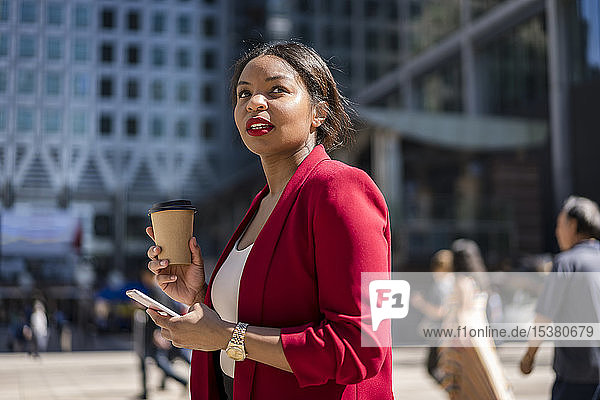Portrait of businesswoman with coffee to go and cell phone  London  UK