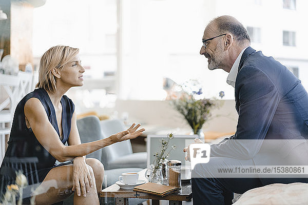 Ein Geschäftsmann und eine Geschäftsfrau treffen sich in einem Café und diskutieren über die Arbeit
