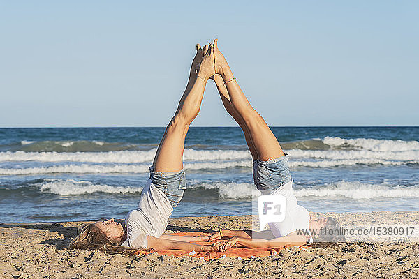 Zwei Frauen praktizieren Acro Yoga am Strand