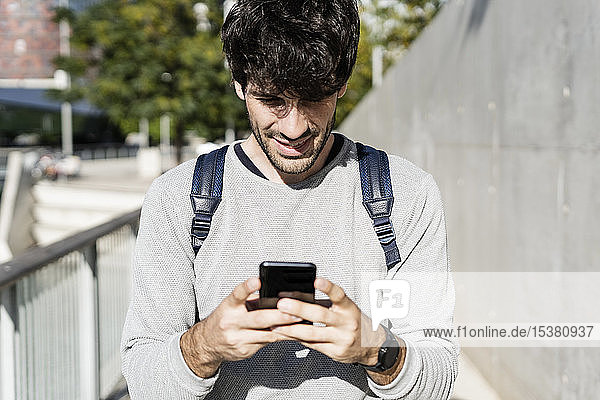 Lächelnder Mann mit Smartphone in der Stadt
