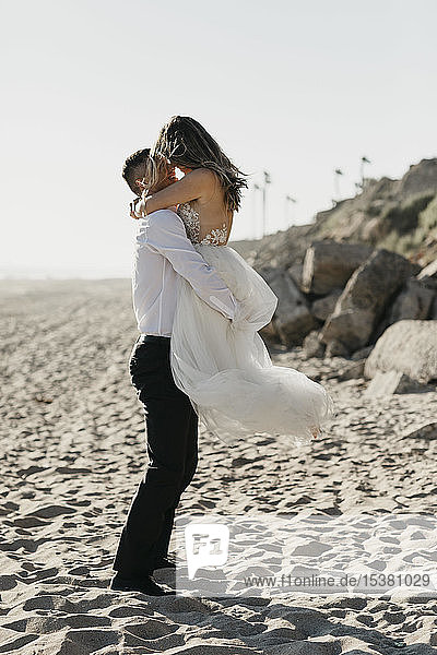 Happy bride and groom hugging on the beach