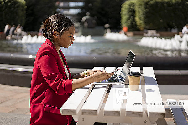 Businesswoman working on laptop outdoors London UK