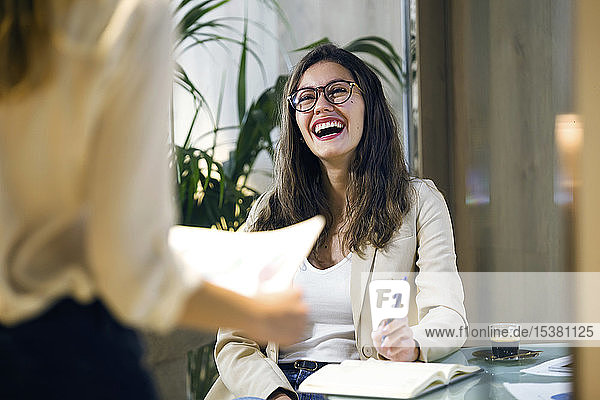 Lachende Geschäftsfrau sieht Kollegin im modernen Büro an