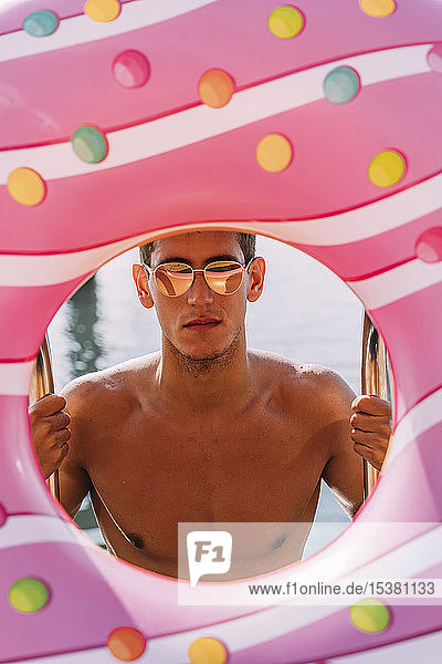 Porträt eines jungen Mannes hinter einem aufblasbaren Schwimmer in Donutform