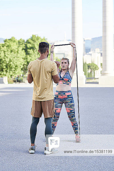 Fitness coach practicing with young woman outdoors in the city