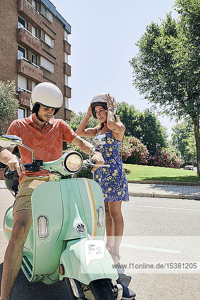 Young couple standing at vintage motor scooter