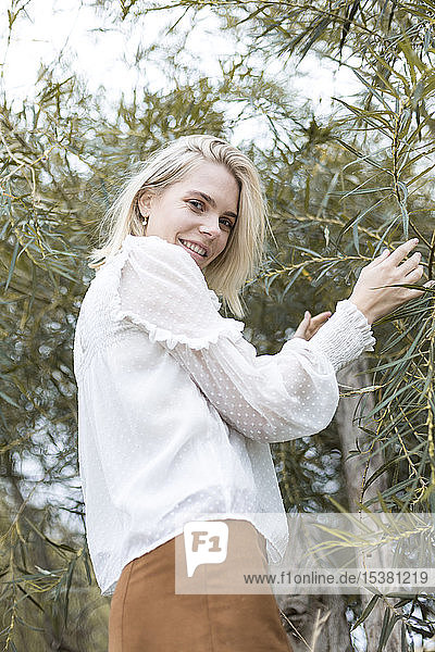 Portrait of blond young woman wearing white blouse outdoors