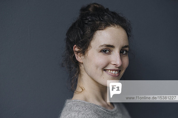 Porträt einer lächelnden jungen Frau vor grauem Hintergrund