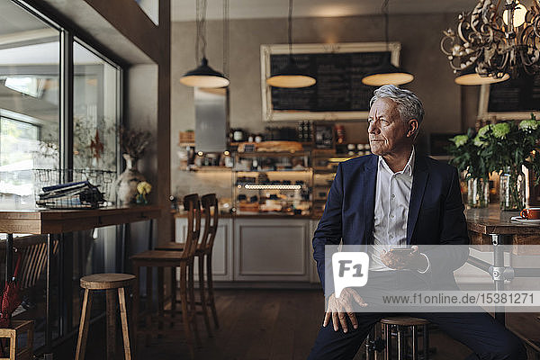 Senior businessman with cell phone in a cafe