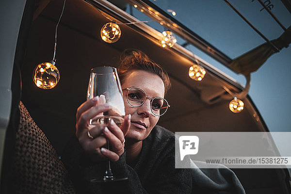 Portrait of woman with glass of white wine in van in the evening